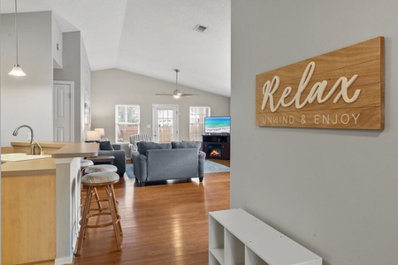 Bright and inviting open-concept living area with cozy seating, vaulted ceilings, and a warm, welcoming vibe—perfect for relaxing after a day at the beach.