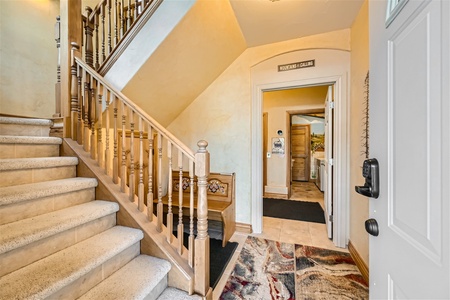 A foyer with a staircase on the left, a wooden bench below the stairs, and a doorway leading to another room on the right. The sign above the door reads "Mountain Calling.