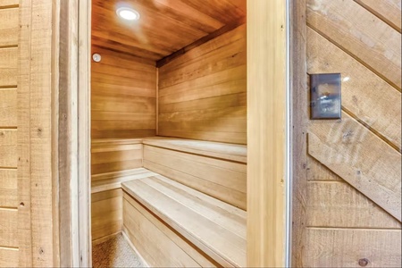 A wooden sauna room featuring built-in benches, warm lighting, and smooth wood paneling on the walls.