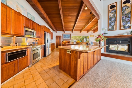 Kitchen with custom koa wood cabinetry, granite counter tops, high end appliances and well appointed cooking accessories. There is also a beautiful, decorative fireplace and gorgeous artwork. Kitchen and decorative fireplace.