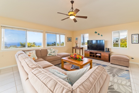 The Living Room features a large sectional couch. Expansive ocean and landscape views from most rooms. There is a large smart TV. The table in the far corner may be used as a second work desk, or can be unfolded into a game, card, poker table