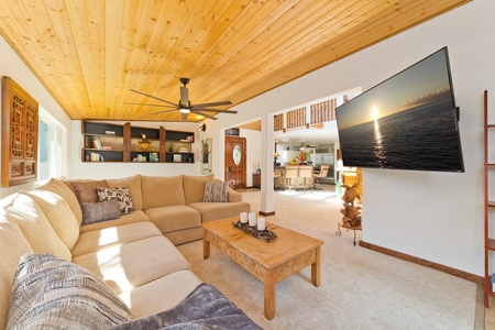 Living room with comfortable sectional, large smart TV. This vantage looks towards formal dining area (new table is behind sectional), entryway and kitchen Living room with large flat screen TV