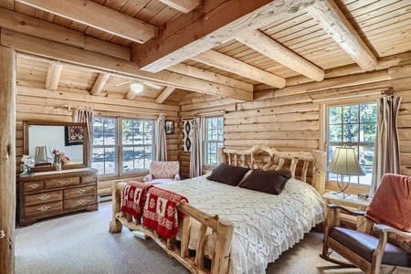 A bedroom in a log cabin with a bed and dresser.