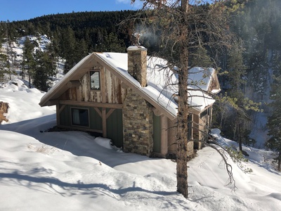 A cabin in the woods covered in snow.