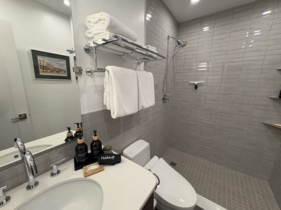 The brand new modern bathroom offers spa-like luxury with a stunning subway tiled walk-in shower, a sleek bidet toilet, and an elegant quartz-topped vanity.