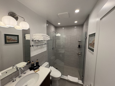 The brand new modern bathroom offers spa-like luxury with a stunning subway tiled walk-in shower, a sleek bidet toilet, and an elegant quartz-topped vanity.