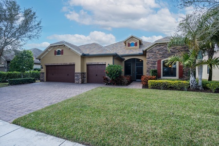 spacious three car garage for your car. Outside elevation with a charming stone accented facade, and lush landscaping