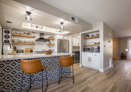 Stylish kitchen with modern amenities, open shelving, and a bold island—perfect for enjoying meals in a warm, inviting space.