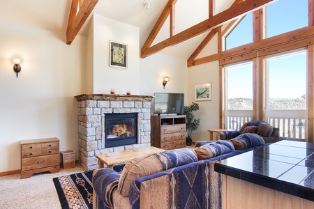 Flat-screen TV and gorgeous stone fireplace in the main living area, floor to ceiling windows offer beautiful mountain views.