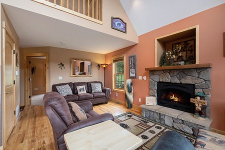 Living room with sofa that seats 3, recliner, end table, fireplace, and vaulted ceiling.