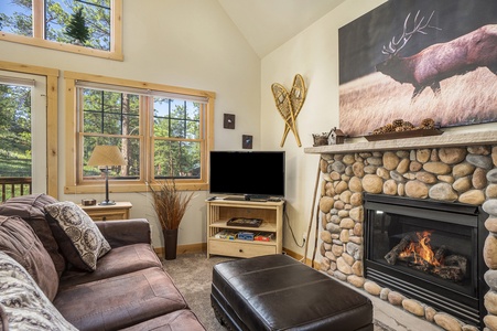 Living room with sofa that seats 3, ottoman, fireplace, and flat screen TV.