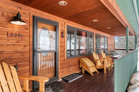 Porch with front door and four Adirondack chairs