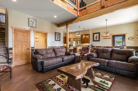 The living area features a large flatscreen TV, a fireplace, rustic wooden accent furniture, and comfy couches