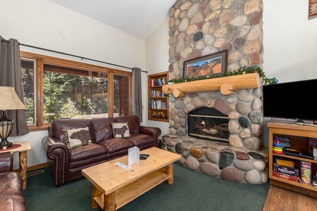 Living room with 2 sofas, a flat screen TV and a stone fireplace.