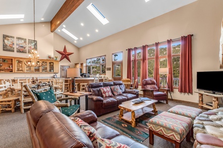 Living room open to dining and kitchen. Seating for 8 on sofas and chairs in living area. Gas fireplace.