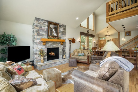 Elk River Cabin Living room with 2 love seats that seat 2 each with ottomans, 2 arm chairs, gas fireplace, and flat screen tv.