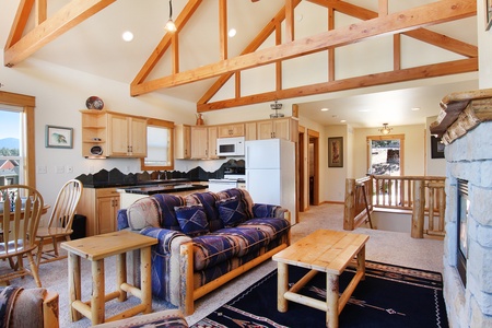 Spacious living area with queen sleeper sofa, fireplace, and flat-screen TV adjacent to the kitchen and dining area. 