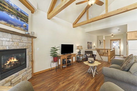 Gorgeous stone fireplace, flat screen TV, and two double-cushion sofas in main living area, opens up to the kitchen/dining area.