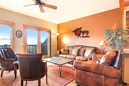 Main living space area with three-cushion sofa, loveseat, and two armchairs. Plenty of space to relax with loved ones around the beautiful stone fireplace.