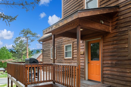 Exterior view of cabin front door, with porch that wraps around to large deck, with private grill.