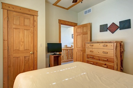 Main level bedroom with queen size bed, located near the entry and the stairwell down to lower level.