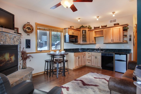 Living/dining area opens up to efficiency kitchen. Stone gas fireplace, bar table with seating for four.