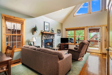 Living room with sofa that seats 4, 2 reclining chairs, fireplace, and flat screen TV.