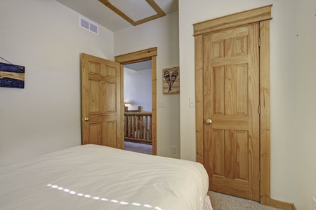 Comfortable queen size bed on the main level, near main entrance and the stairwell down to lower level.