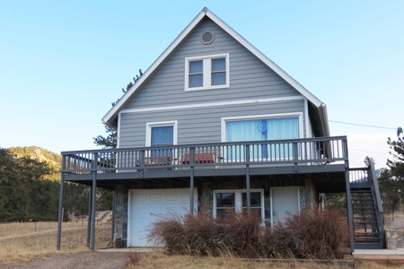 View of the front of the home with garage and stairs that lead to the deck and front door