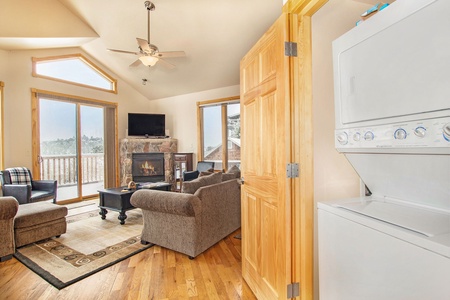 Living room with queen sleeper sofa, oversized chair with ottoman with gas fireplace and flatscreen TV. Stackable washer/dryer