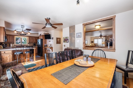 Beautiful spacious kitchen, Dining table for 8, Kitchen bar top with two stools, ceiling fan, and pass through window into the living room.