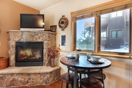 Bar height table with seating for four adjacent to stone fireplace.