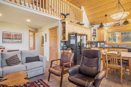 Spacious living room with vaulted ceiling, sofa that seats 3, coffee table, and two chairs.