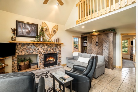 Open concept living room with fireplace, vaulted ceilings, sleeper sofa that seats 3, murphy bed with shelves, 2 leather recliners, small end table, and flat screen TV. Guests may use either the sleeper sofa or the murphy bed.