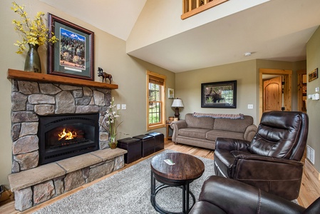 Living room with fireplace, 2 leather arm chairs, small round table, sofa that seats 4, and 3 small ottomans.