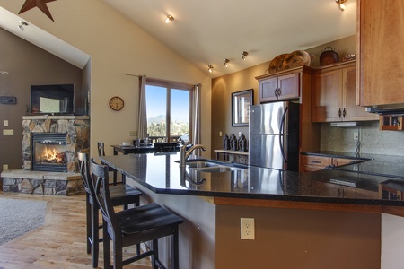 The well equipped kitchen looks out into the living room with fireplace and flat screen TV 