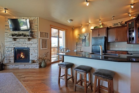 Kitchen area has breakfast bar with seating. Opens to living room with fireplace and flat screen TV