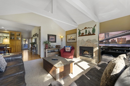 Spacious living room features a gas fireplace, 2 sofas, 1 side arm chair, and a flat screen TV.