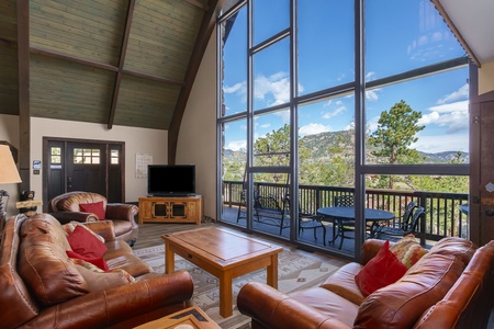 Living Room features floor to ceiling  windows overlooking the deck with mountain views