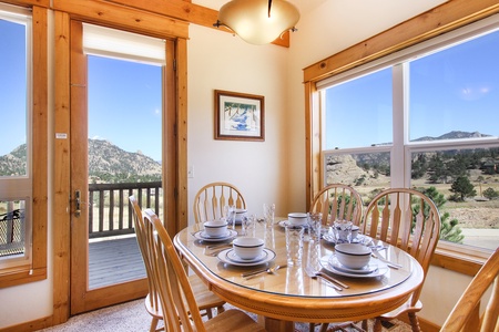 Dining table with seating for six surrounded by windows and beautiful mountain views.