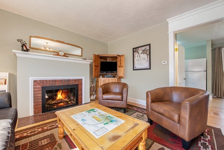 Your Vacation House Estes Park, Living room with coffee table, two side chairs, flat screen tv, and gas fireplace.