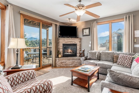 Large living room with oversized chair and L shaped sofa. Flat screen TV with gas fireplace and panoramic views out the sliding glass doors. 