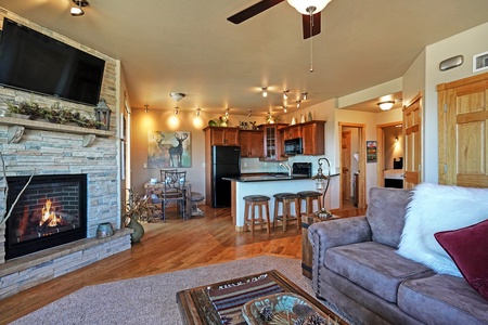 Open concept living room/kitchen with gas fireplace, queen sleeper sofa, breakfast bar with seating and dining table that seats six. 