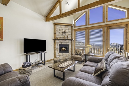 Living area with gas fireplace, queen sleeper sofa, flat screen TV and lots of windows. 