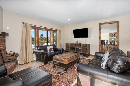 Snowline Vista Lodge Estes Park, Spacious family room with two leather love seats and a couch chair with a foot rest.