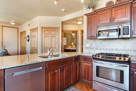 Open kitchen includes gas stove, dishwasher, full size refrigerator, microwave.