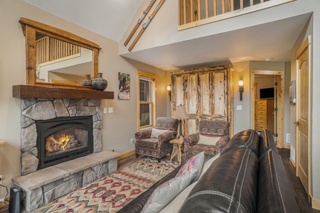 Living room with reclining sofa and two chairs, end table with lamp, murphy bed, and fireplace.