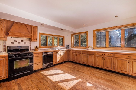 Open kitchen with many windows lets in ample natural light.  Kitchen has a hooded gas range.