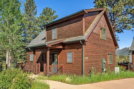 Exterior of cabin, with small porch that wraps around to deck, and front door.