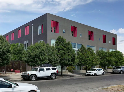 A building with red shutters and cars parked in front of it.